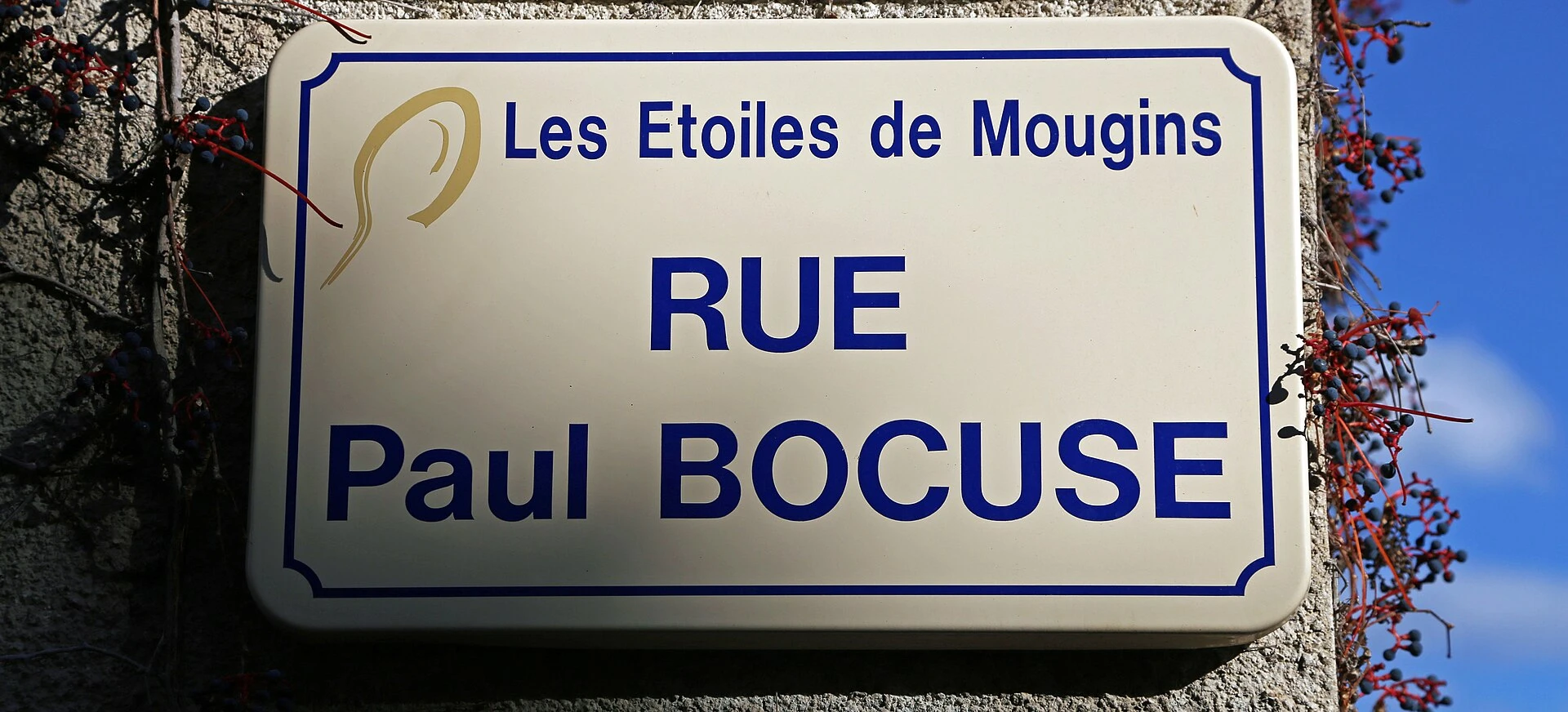 Street sign for Rue Paul Bocuse in Mougins, under the logo of the Étoiles de Mougins festival